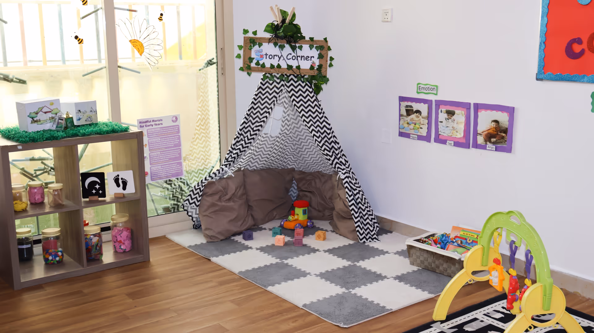 Children's story corner with a black and white tent, cushions, colorful blocks, and educational toys in a classroom.