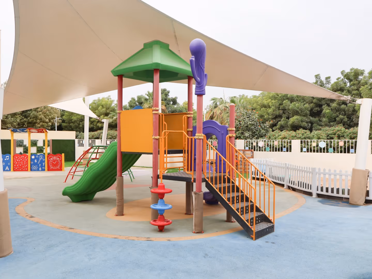 Colorful children's playground with slide, stairs, and climbing structures under a white canopy.