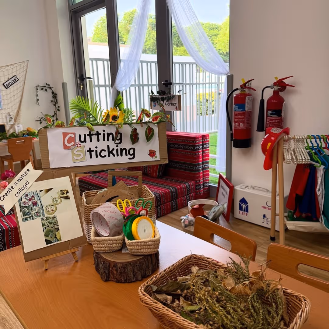 Classroom cutting and sticking activity corner with scissors, baskets, natural materials, and a sign that says 'Cutting & Sticking'.